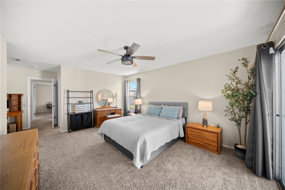 27879 Foxfire Street Menifee, CA 92586 - Photo 29 of 36 a spacious bedroom with a bed a dresser and a chandelier