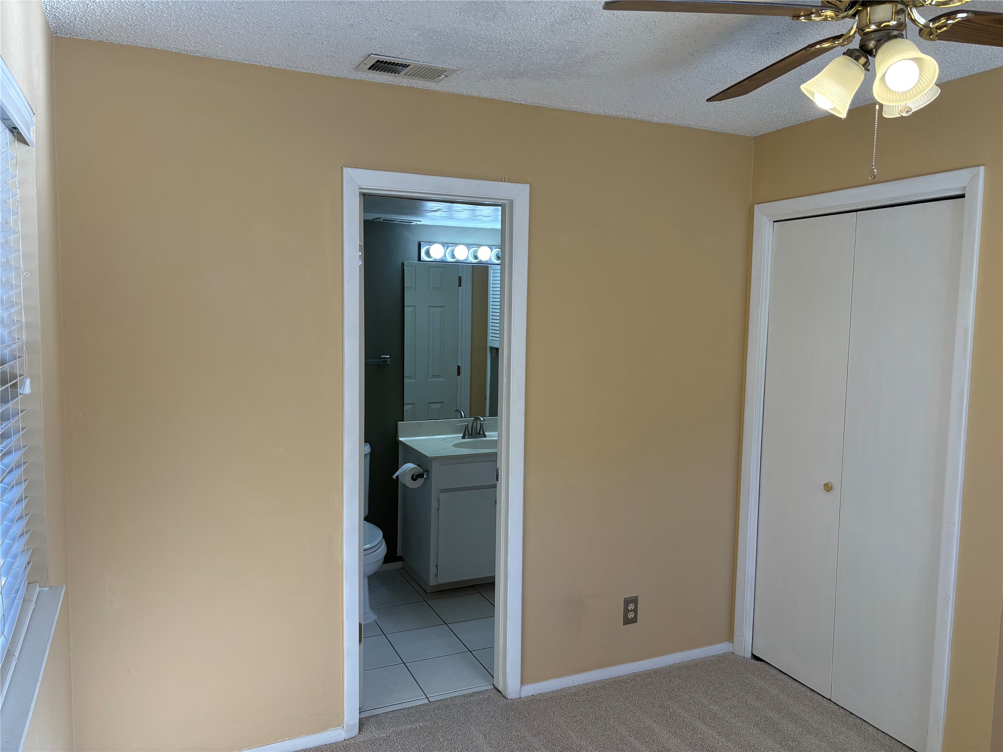 9226 Jollyville Road, Unit 144 Austin, TX 78759 - Photo 17 of 40 Unfurnished bedroom featuring a closet, a textured ceiling, light carpet, a ceiling fan, and ensuite bathroom