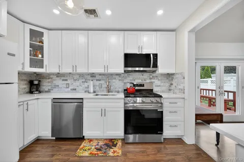 a kitchen with stainless steel appliances granite countertop a stove top oven a sink dishwasher and a microwave oven with cabinets