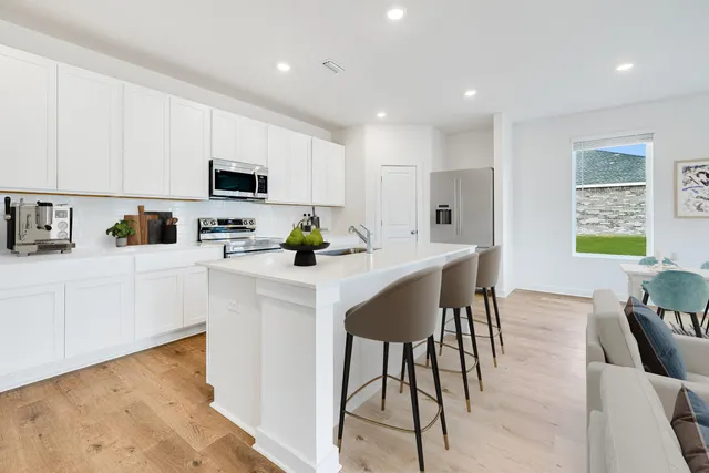 a kitchen with stainless steel appliances a white table chairs and a refrigerator