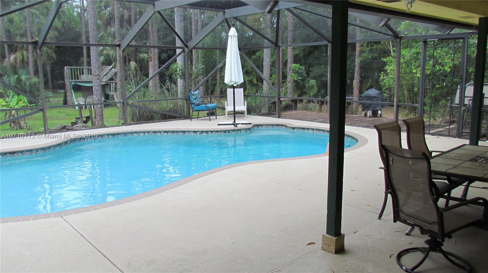 10825 Sandy Run Road Jupiter, FL 33478 - Photo 28 of 31 a swimming pool with outdoor seating and yard