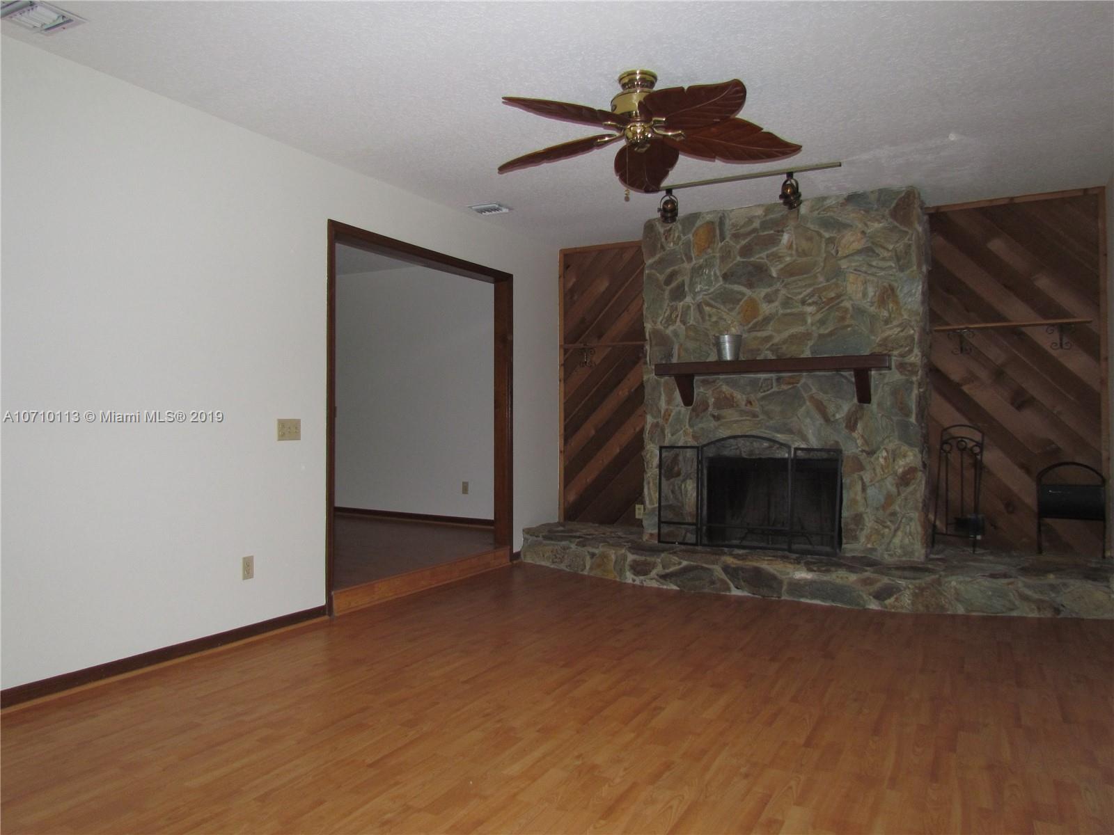 10825 Sandy Run Road Jupiter, FL 33478 - Photo 7 of 31 an empty room with fireplace and a view of kitchen