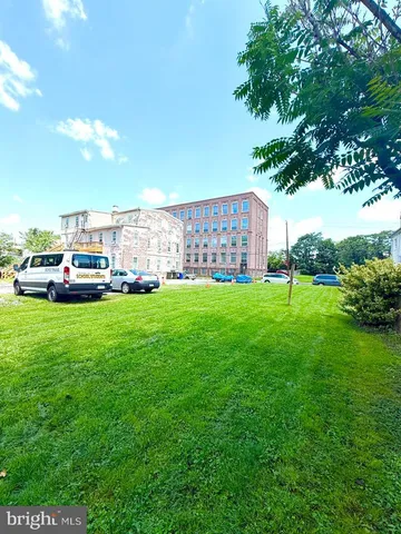 a view of yard with house and car parked in the background