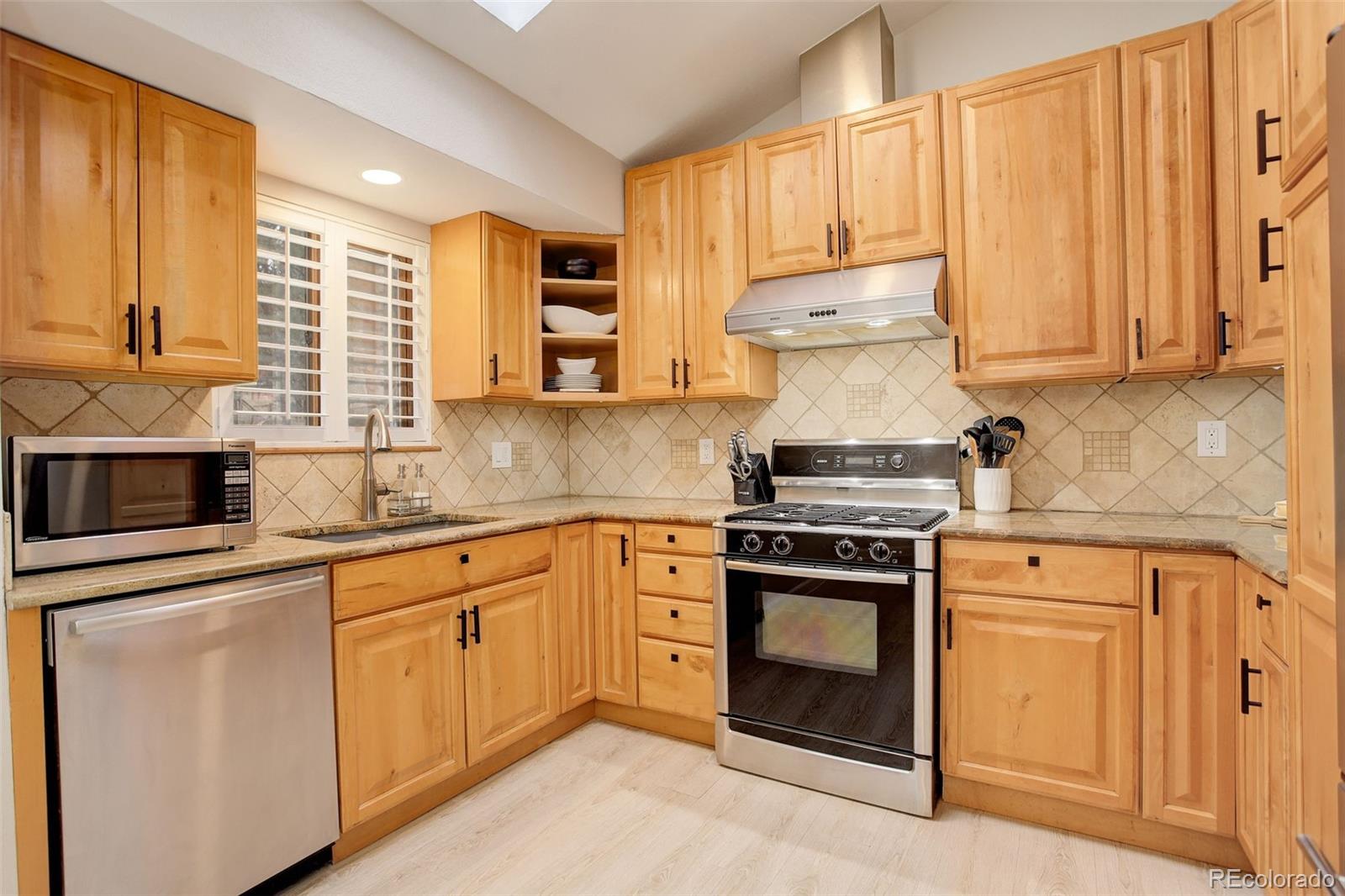 6997 South Columbine Road Evergreen, CO 80439 - Photo 7 of 40 a kitchen with stainless steel appliances granite countertop white cabinets and a stove top oven