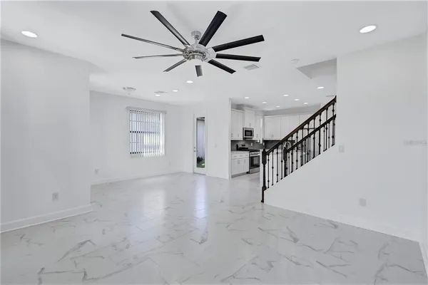 a view of a livingroom with a ceiling fan & windows