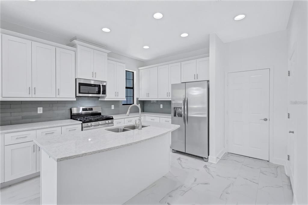 5830 Circa Fishhawk Boulevard Lithia, FL 33547 - Photo 15 of 37 a kitchen with a sink a refrigerator a microwave and cabinets