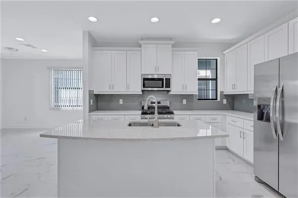 a kitchen with white cabinets and window