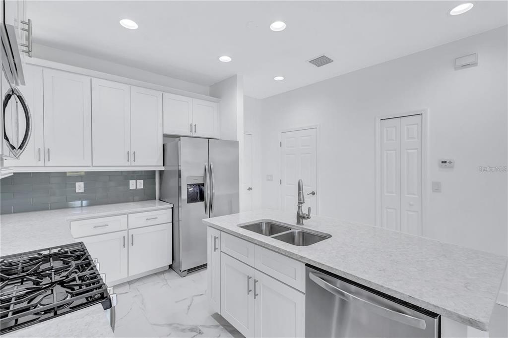 5830 Circa Fishhawk Boulevard Lithia, FL 33547 - Photo 18 of 37 a kitchen with white cabinets and stainless steel appliances