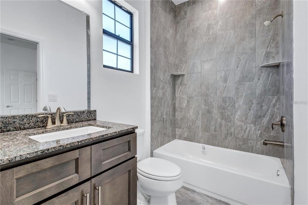 5830 Circa Fishhawk Boulevard Lithia, FL 33547 - Photo 29 of 37 a bathroom with a granite countertop sink toilet and bathtub