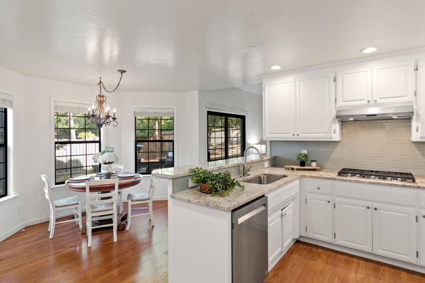 3017 Lopez Road Pebble Beach, CA 93953 - Photo 9 of 30 a kitchen with stainless steel appliances granite countertop a stove top oven a sink dishwasher and white cabinets with wooden floor