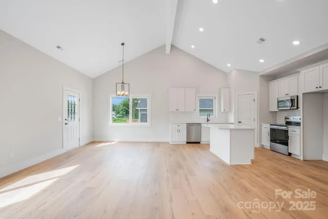 a view of kitchen with microwave a stove and white cabinets