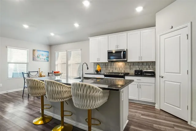 a kitchen with kitchen island granite countertop a stove a sink a dining table and chairs