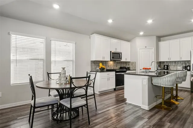 a kitchen with a table chairs microwave and cabinets