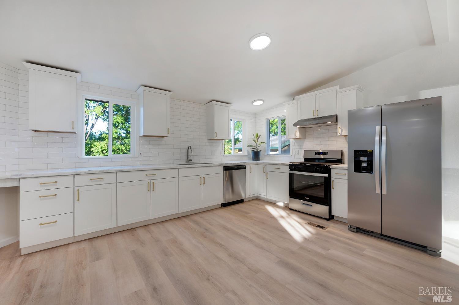 a kitchen with white cabinets stainless steel appliances and window