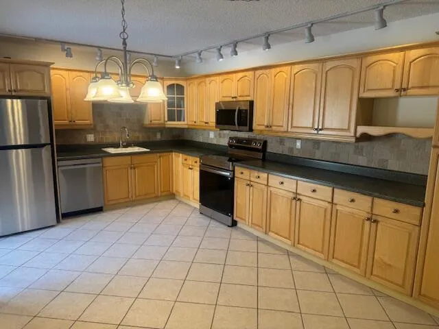 a kitchen with stainless steel appliances granite countertop a refrigerator a sink a stove top oven and granite countertops