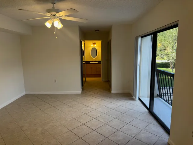an empty room that has a window and a ceiling fan