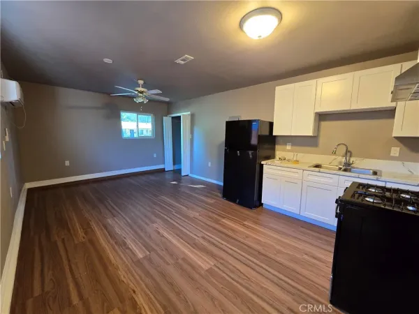 a kitchen with stainless steel appliances granite countertop a refrigerator a sink dishwasher a stove and white countertops with wooden floor