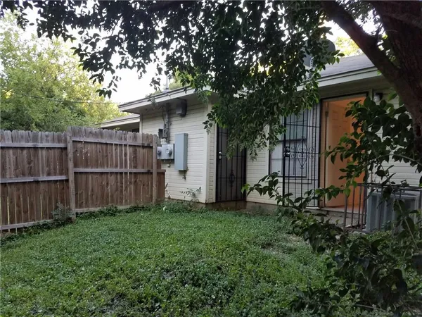 a view of a backyard with plants and large trees