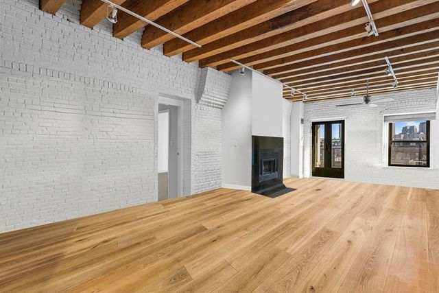 a view of an empty room with wooden floor and a ceiling fan