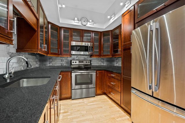 a kitchen with stainless steel appliances granite countertop a stove a sink and a refrigerator