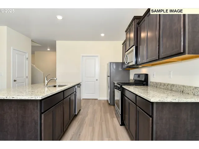 a kitchen with stainless steel appliances granite countertop a sink a stove and a wooden cabinets
