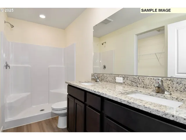 a bathroom with a granite countertop sink a toilet and shower