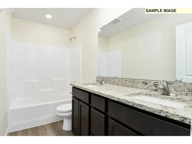 a bathroom with a granite countertop sink a toilet and shower