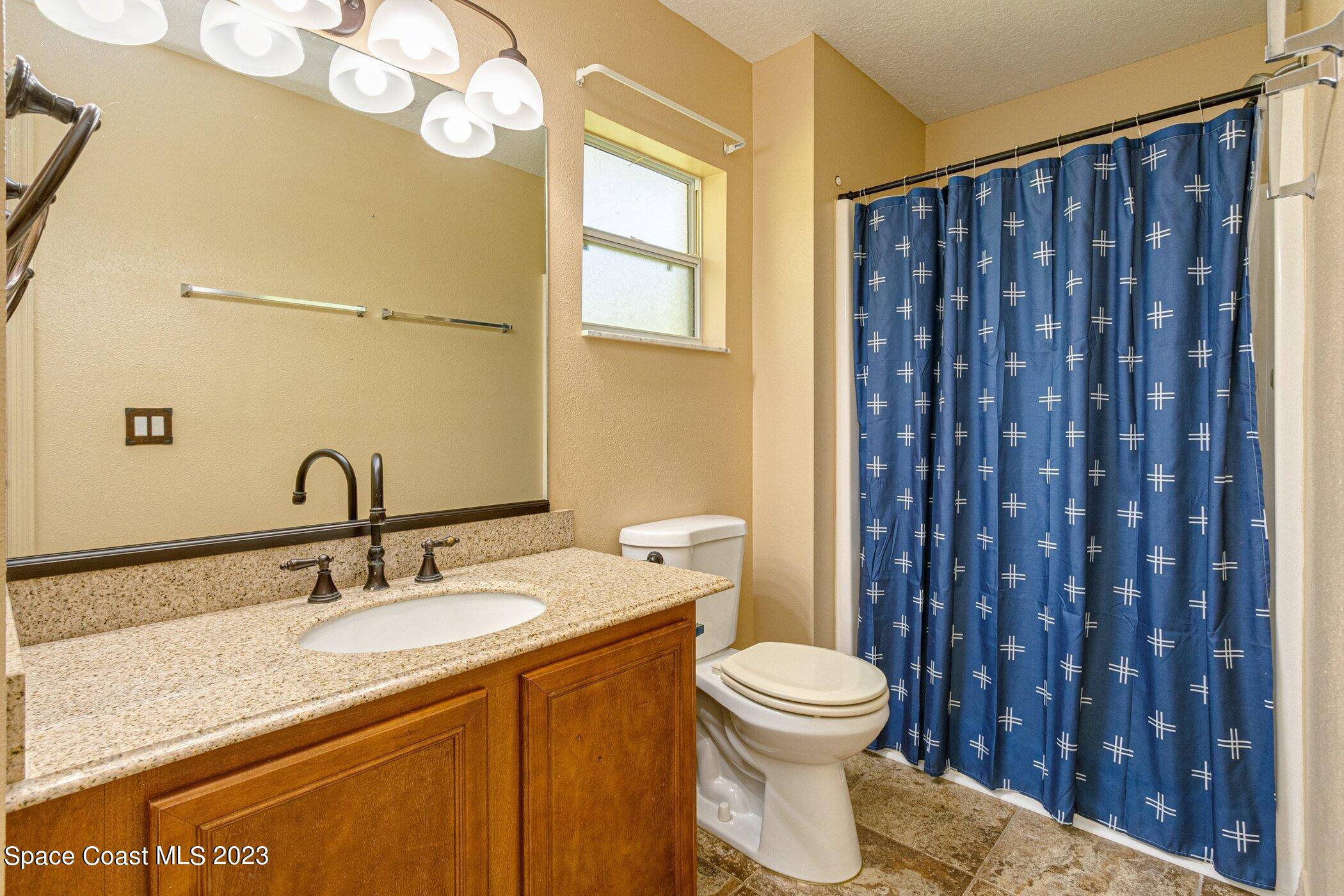 1371 Darrow Road Southwest Palm Bay, FL 32908 - Photo 13 of 21 a bathroom with a granite countertop toilet sink and mirror
