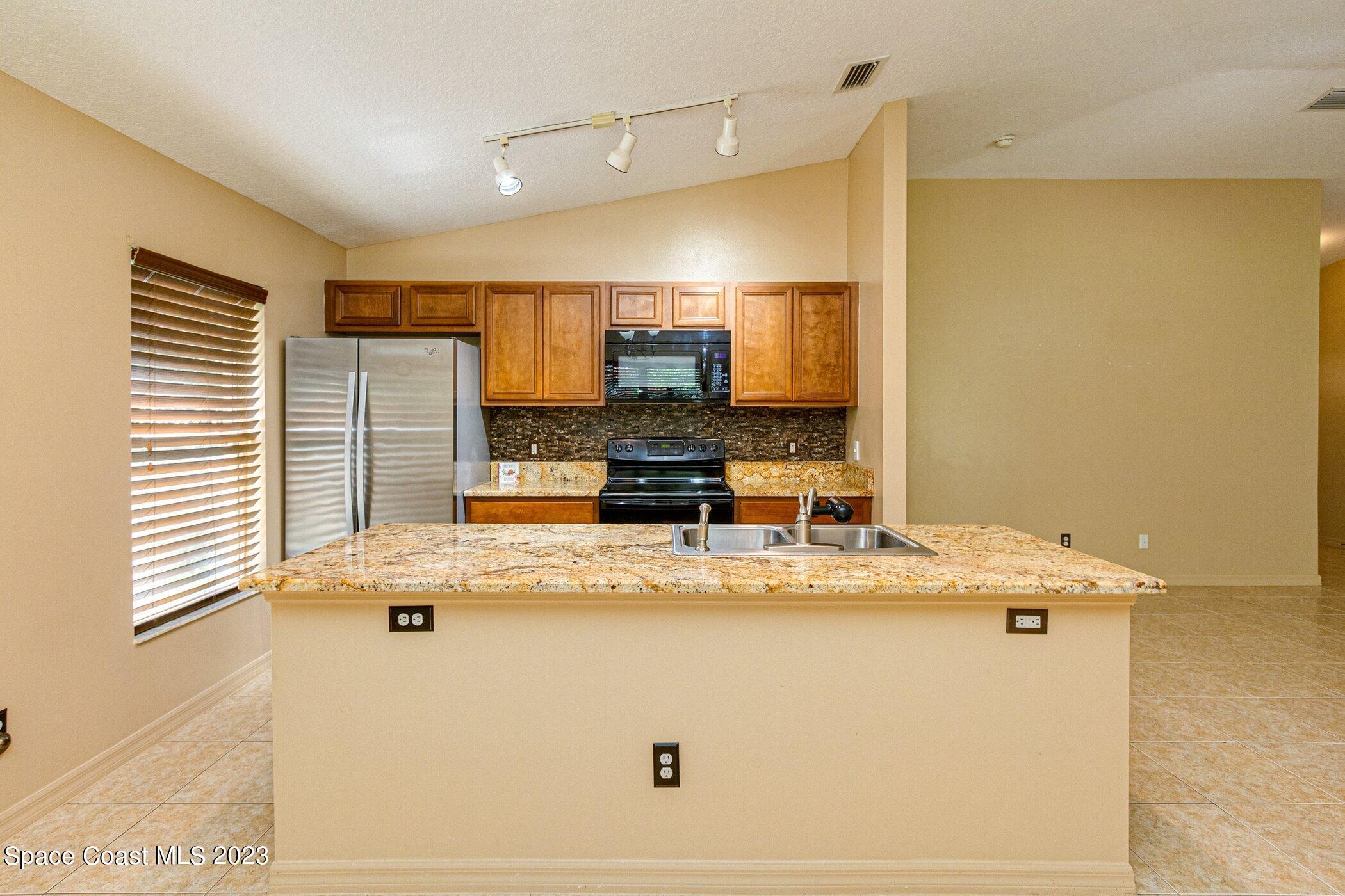 1371 Darrow Road Southwest Palm Bay, FL 32908 - Photo 3 of 21 a view of kitchen with stainless steel appliances granite countertop refrigerator sink and stove