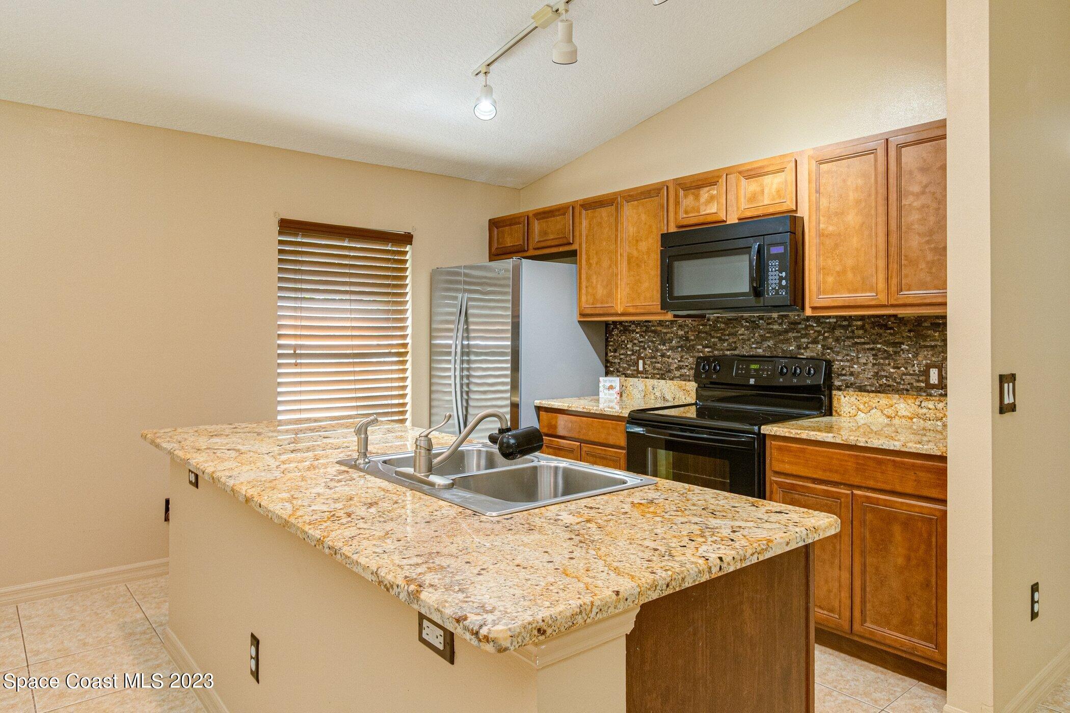 1371 Darrow Road Southwest Palm Bay, FL 32908 - Photo 4 of 21 a kitchen with stainless steel appliances granite countertop a sink stove and microwave