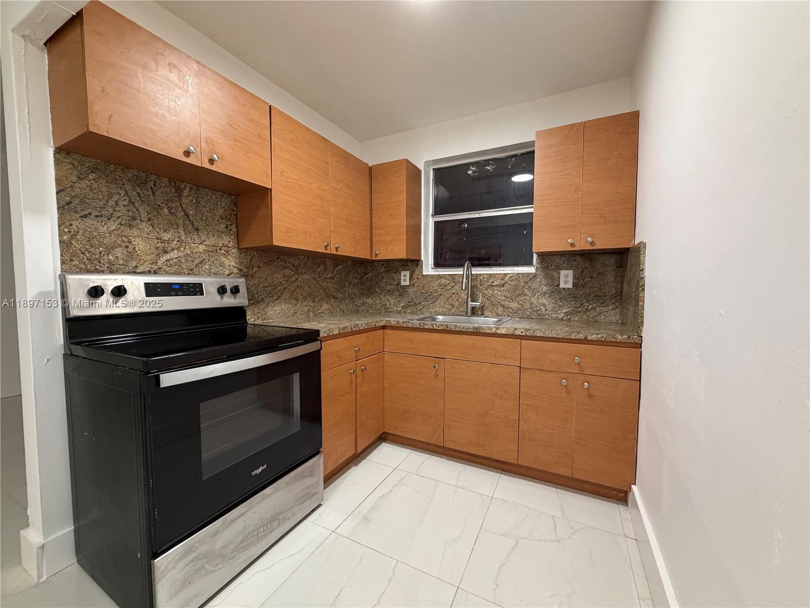 3100 Northwest 135th Street, Unit 4 Opa-Locka, FL 33054 - Photo 2 of 5 a kitchen with stainless steel appliances granite countertop a sink stove and microwave