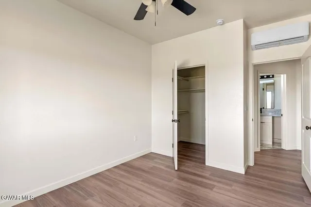 an empty room with wooden floor and ceiling fan