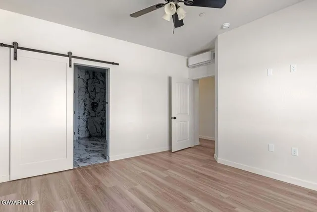 a view of an empty room with wooden floor and a ceiling fan