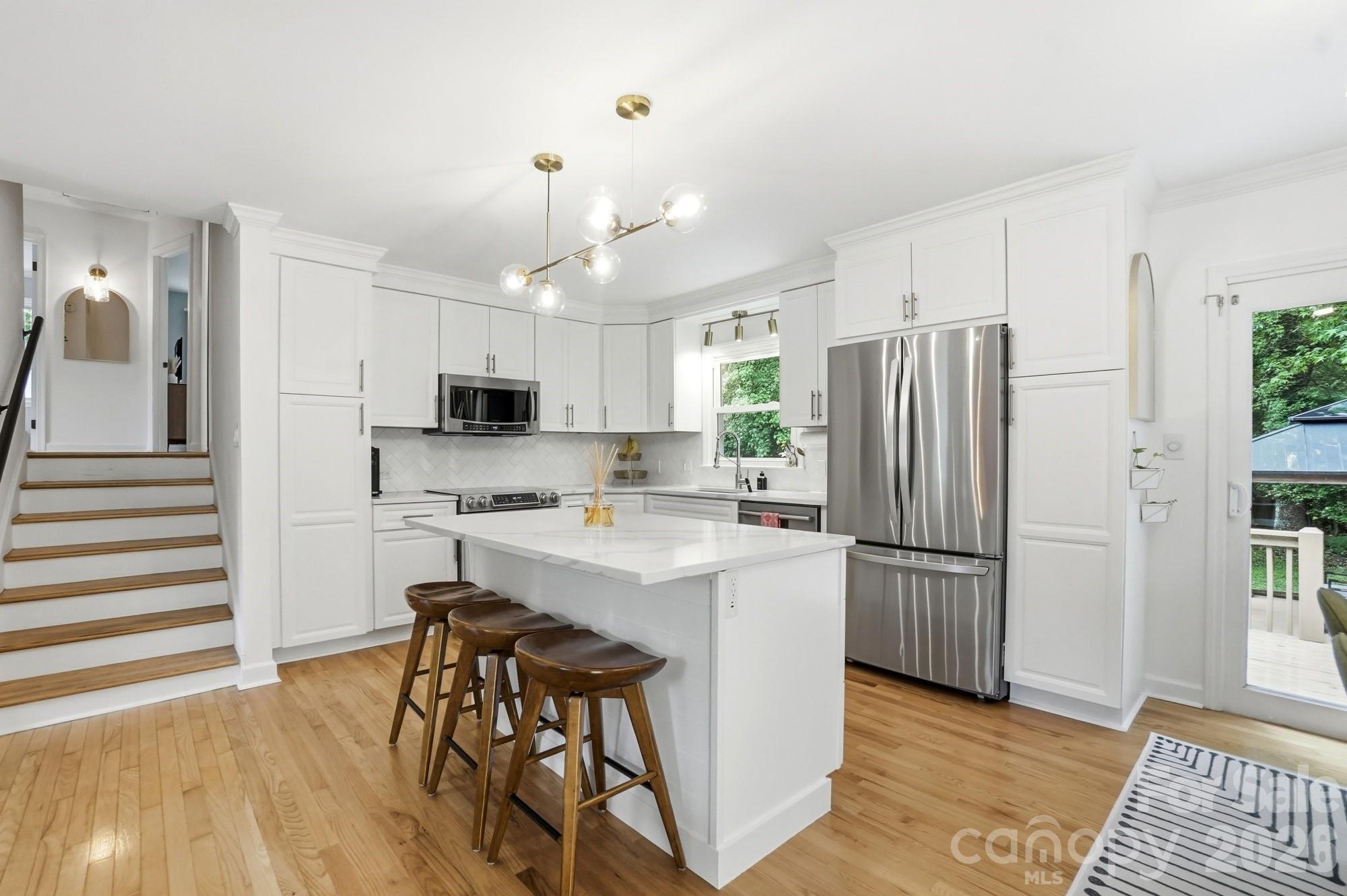 824 Riverwood Road Charlotte, NC 28270 - Photo 5 of 37 a kitchen with stainless steel appliances a refrigerator a stove a sink dishwasher and white cabinets with wooden floor