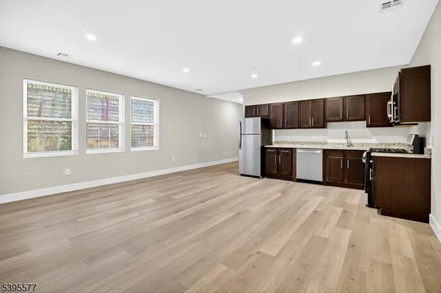 a view of kitchen with kitchen island a sink wooden floor and a refrigerator