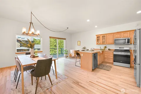 a living room with a dining table wooden floor and a floor to ceiling window