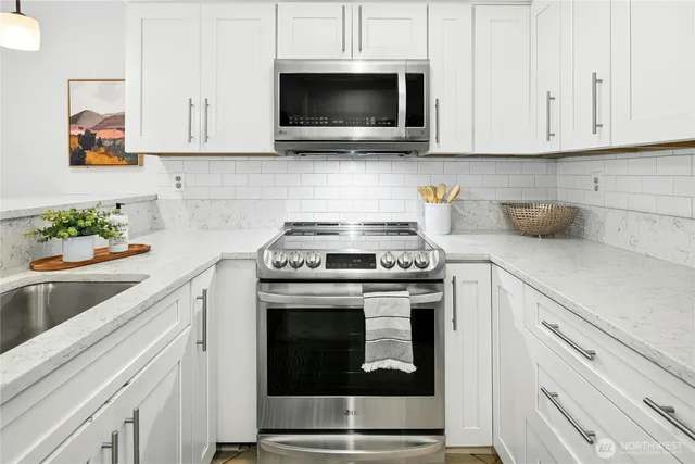 a kitchen with stainless steel appliances granite countertop a stove a microwave and cabinets
