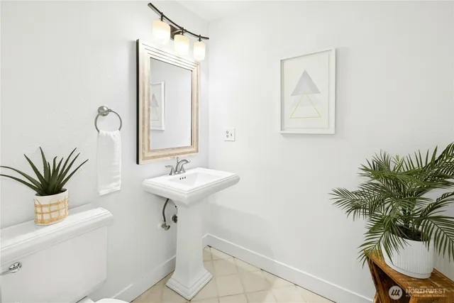 a bathroom with a sink a mirror and a potted plant