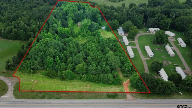 an aerial view of residential house with outdoor space and trees all around