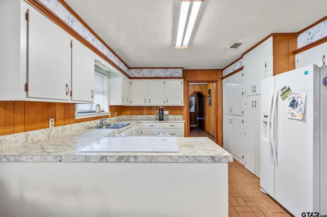 a large kitchen with stainless steel appliances granite countertop a refrigerator and a sink