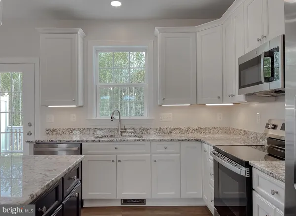 a kitchen with stainless steel appliances granite countertop a sink a stove a microwave and cabinets