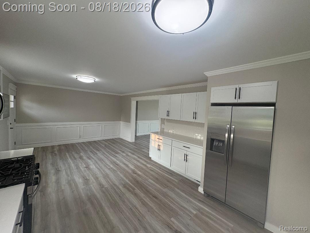 32563 Sutton Road New Baltimore, MI 48047 - Photo 20 of 43 Modern kitchen featuring stainless steel appliances, white cabinetry with dark hardware, a white subway tile backsplash, and wood-finish flooring
