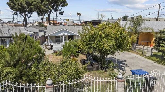 a view of a house with a small yard and large trees