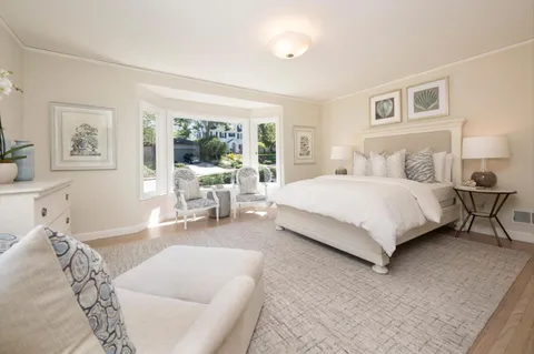 a bedroom with a large bed couch and a large window