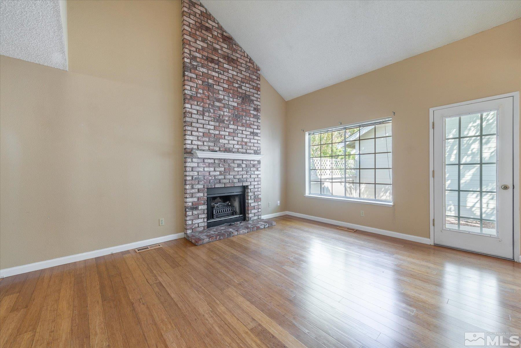 1910 Tuolumne Drive Reno, NV 89523 - Photo 8 of 36 an empty room with wooden floor fireplace and windows