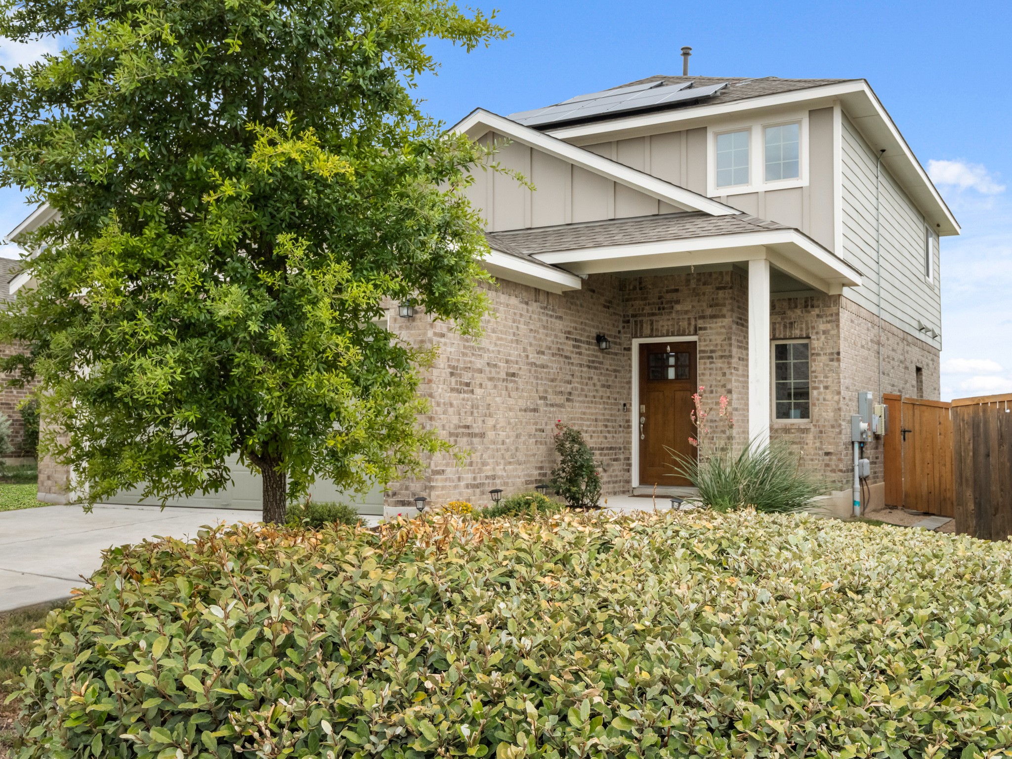 574 Nautical Loop Kyle, TX 78640 - Photo 2 of 23 A welcoming front entrance features brick and siding, complemented by lush landscaping and a paved driveway.