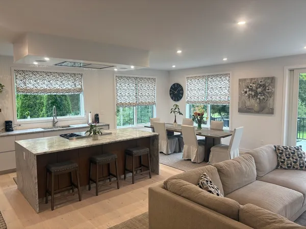a living room with furniture kitchen view and a large window