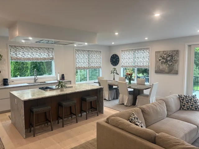 a living room with furniture kitchen view and a large window