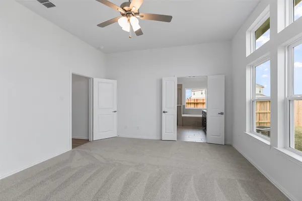 a view of an empty room with a window and a ceiling fan