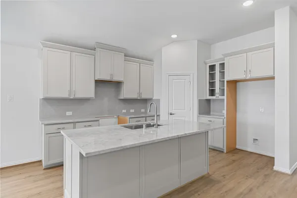 a kitchen with a sink a refrigerator and white cabinets